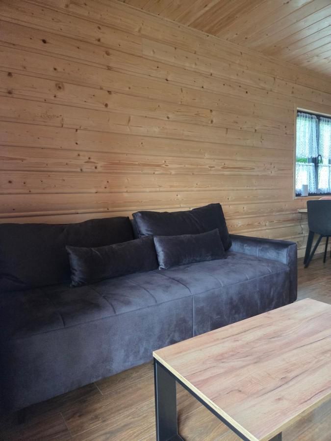 Salon z welurową kanapą i drewnianą ścianą
